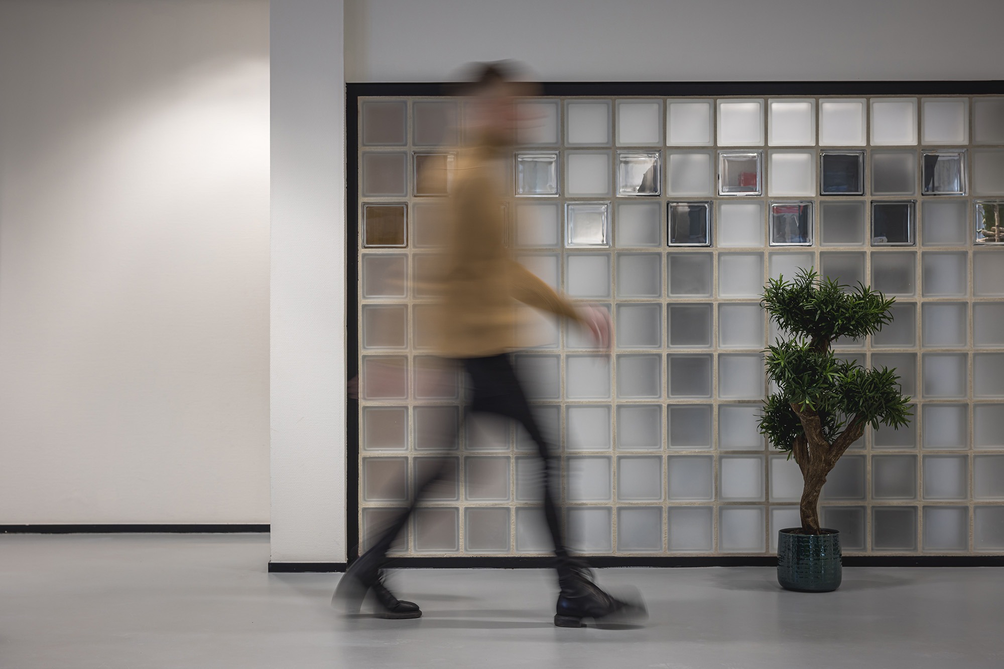 Medewerker van Factor Werkt loopt door een modern en licht kantoorinterieur met planten.