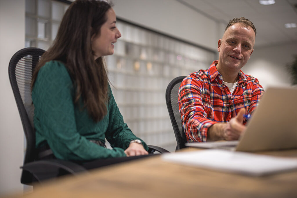 Adviseur van Factor Werkt in gesprek met een vrouwelijke klant aan een houten tafel.